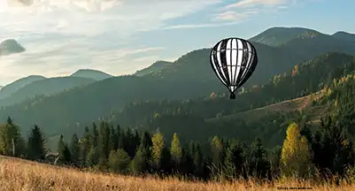 Foto einer alten Häuserreihe an der Stadtmauer mit Blumen vor der Haustür. Darauf geiehcnet eine Frau, die in der Hocke etwas fotografiert.